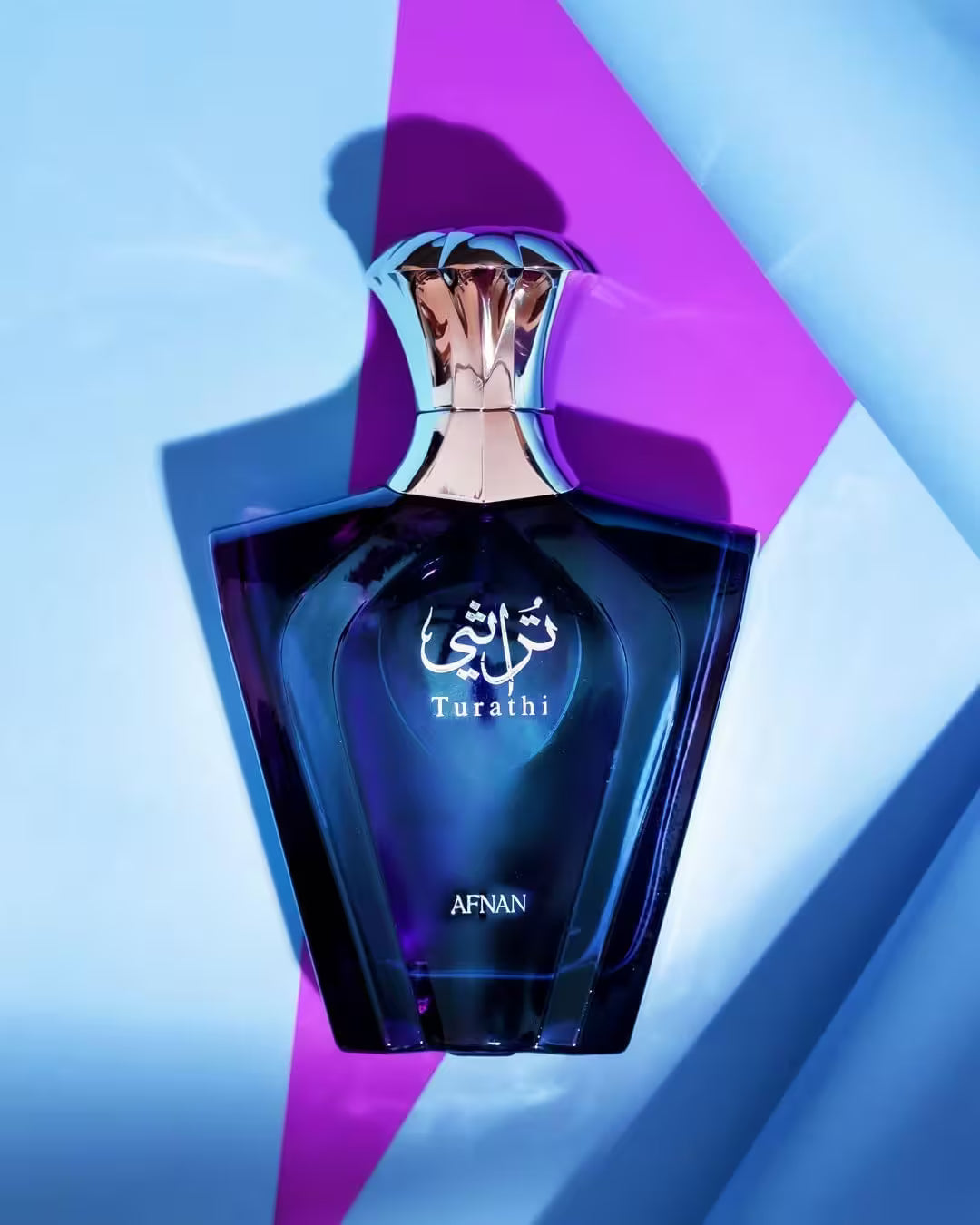 Blue perfume bottle with 'Turathi' and 'Afnan' branding on a geometric background
