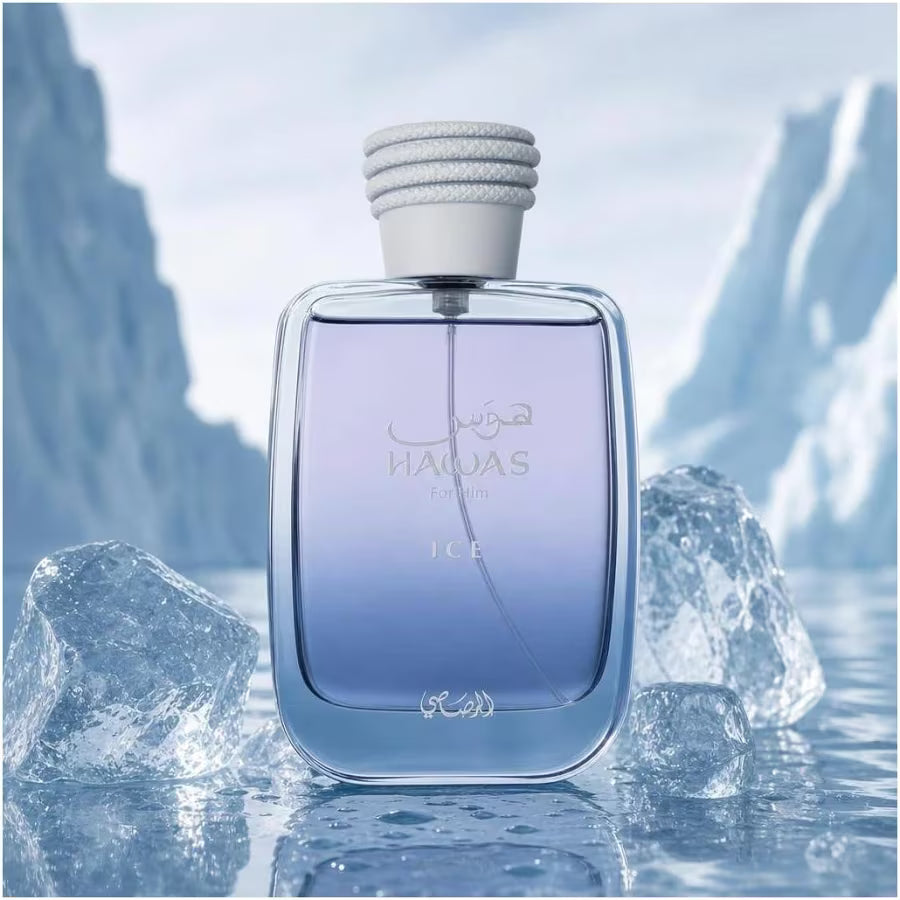 A rectangular glass perfume bottle labeled NAQAS ICE, filled with a light blue liquid, set against an icy mountain background with ice cubes in the foreground.