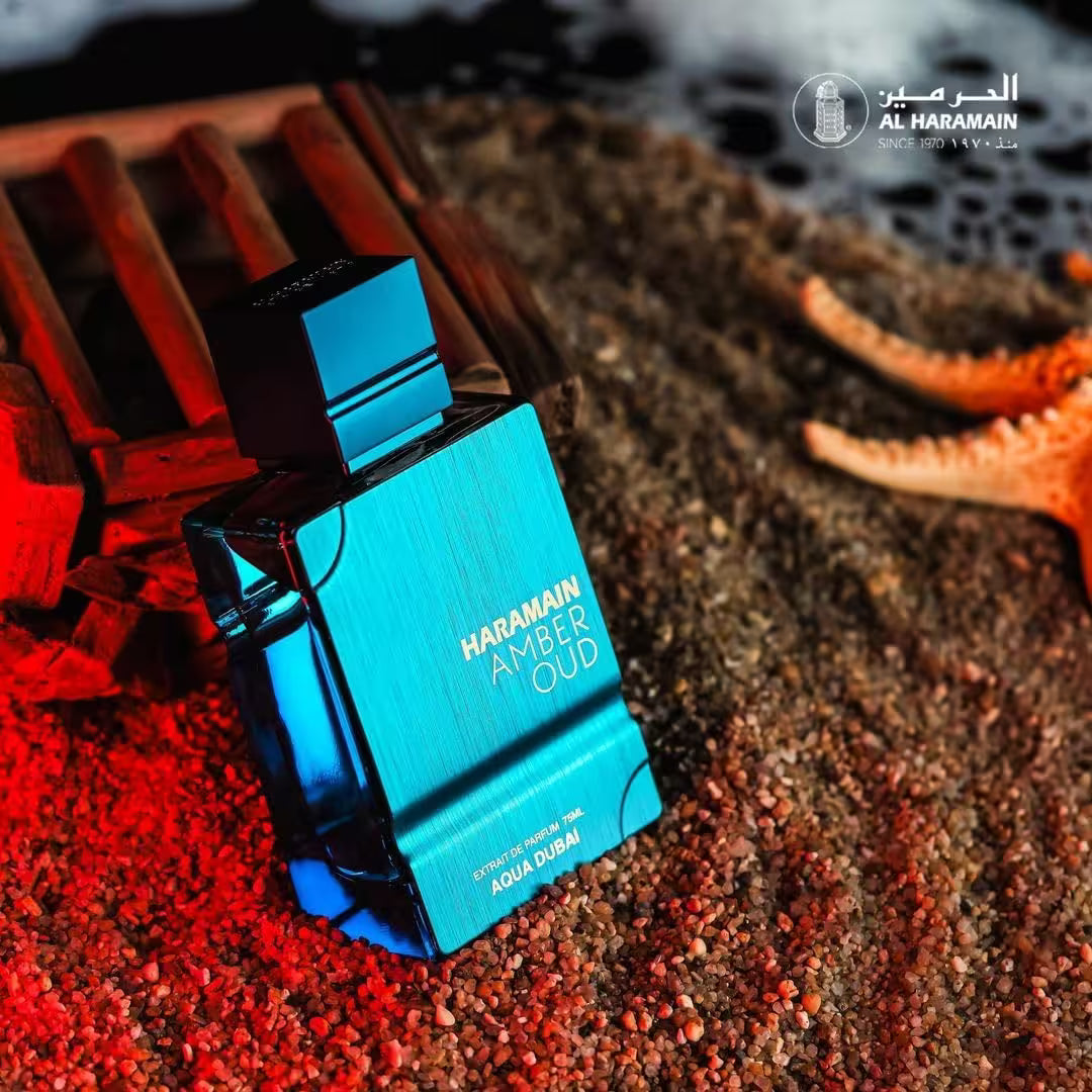 Haramain Amber Oud perfume bottle on a textured surface with starfish