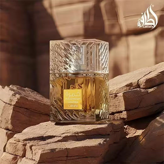 A bottle of Lattafa Arabia Darwish perfume with a textured clear glass cap and golden liquid, resting on a rocky surface with a warm desert canyon background.