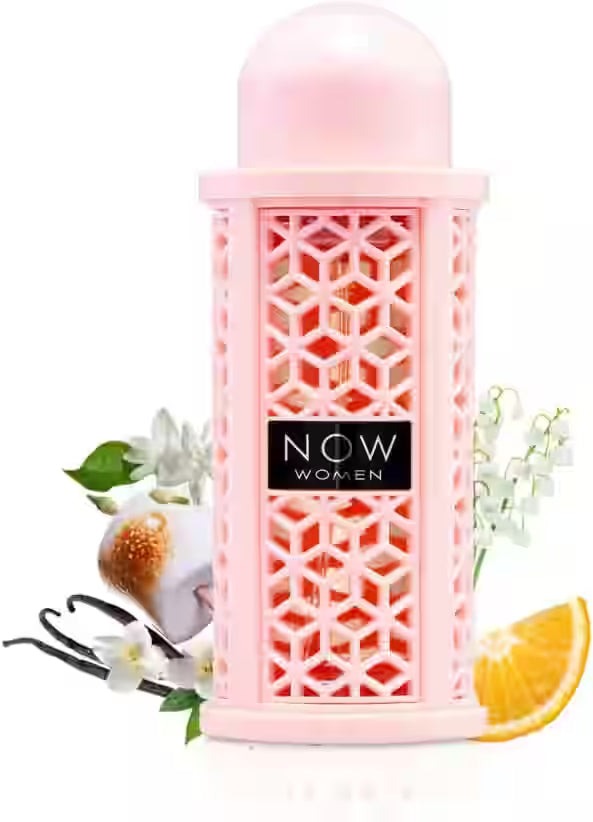 A pink cylindrical perfume bottle with a geometric patterned front and a black label reading 'NOW WOMEN' in white text. The bottle is centered on a white background with decorative floral and citrus props around it.